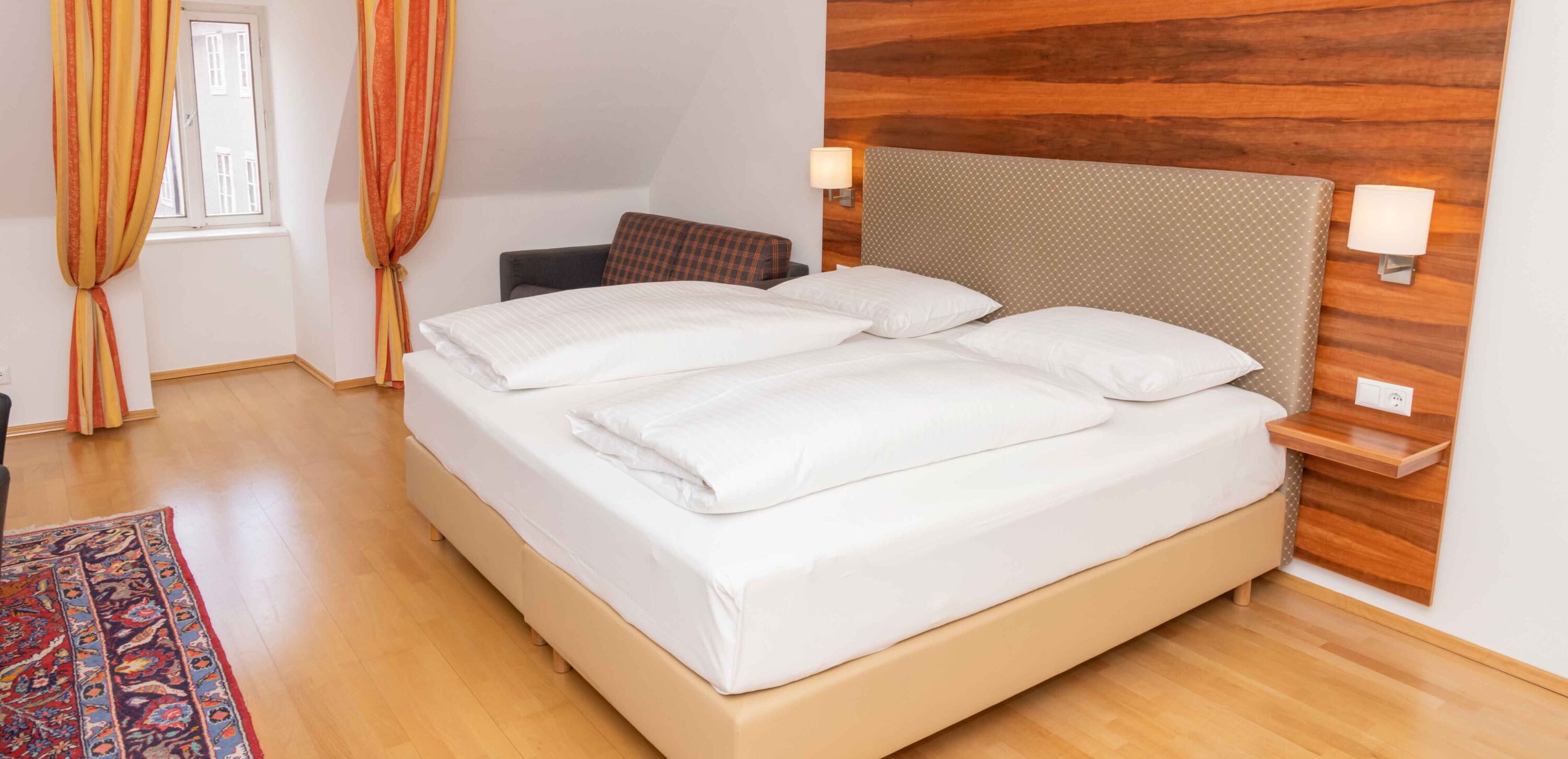 Foto zeigt helle Familiensuite mit Doppelbett, Ausziehcouch und Fenster.