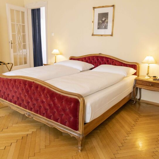 Bild zeigt Hotelsuite mit rotem Samtbett und Mobiliar im Jugendstil.