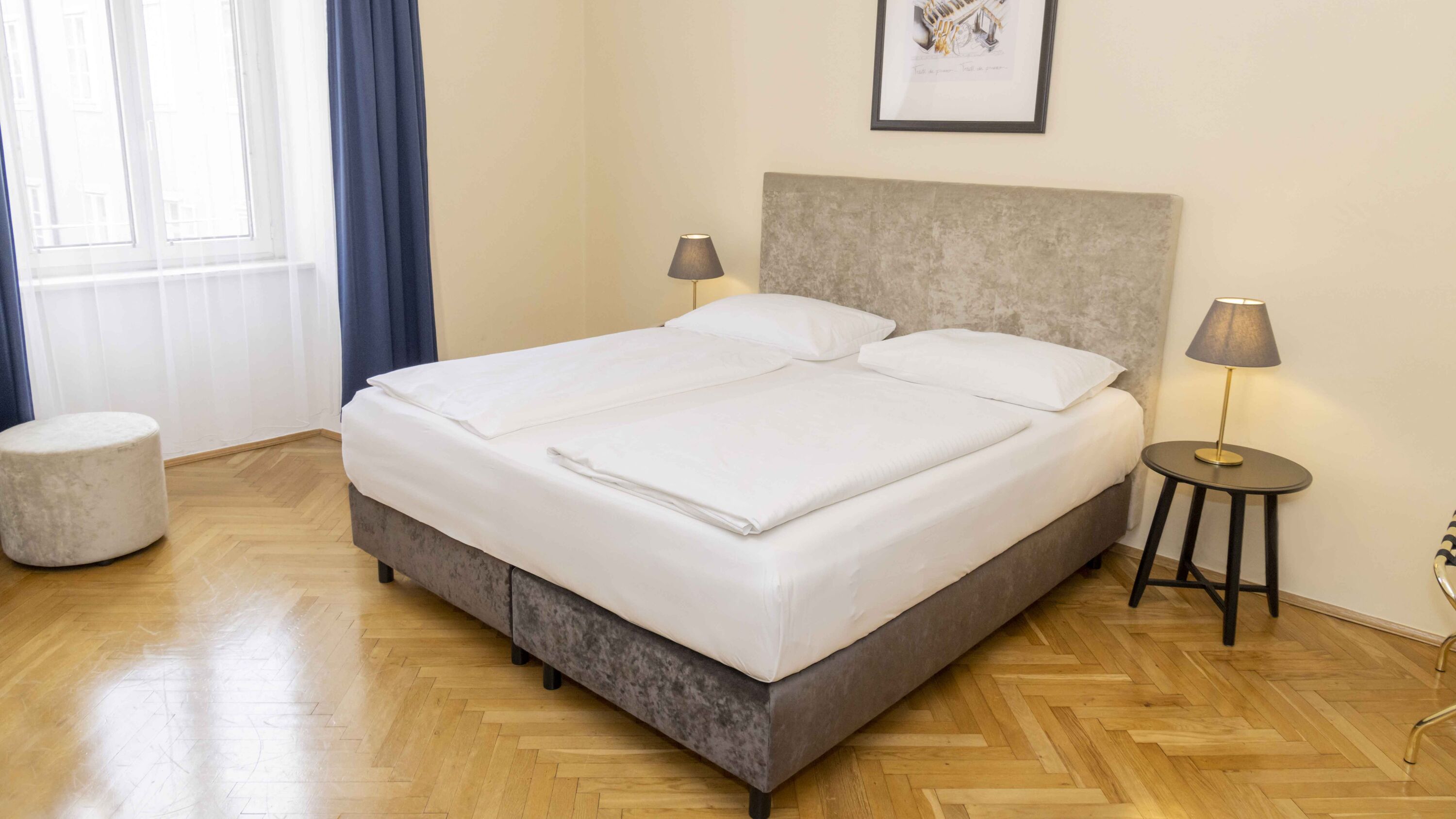 Bild zeigt helles Hotelzimmer mit Doppelbett und Parkettboden.