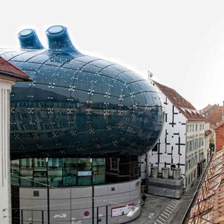 Bild zeigt Mann und Frau aus dem Fenster schauend, mit Blick aufs Grazer Kunsthaus.