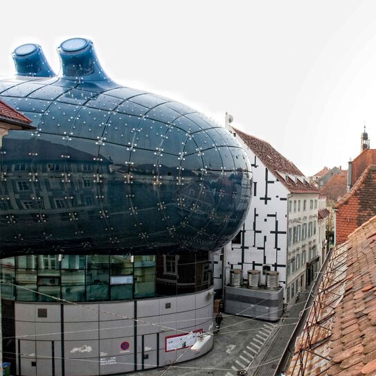 Bild zeigt Mann und Frau aus dem Fenster schauend, mit Blick aufs Grazer Kunsthaus.